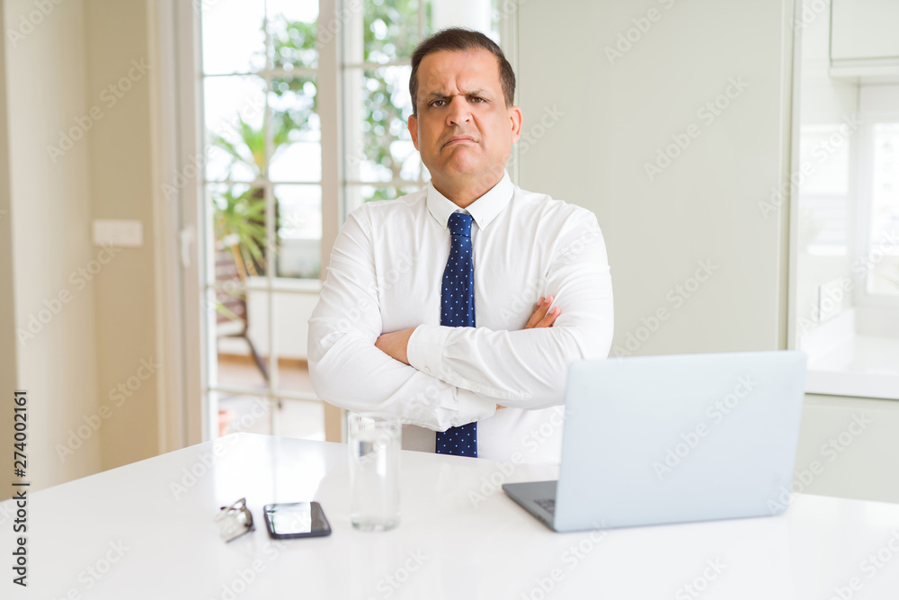 Middle age business man working with computer laptop skeptic and nervous, disapproving expression on face with crossed arms. Negative person. Middle age business man working with computer laptop skeptic and nervous, disapproving expression on face with crossed arms. Negative person.