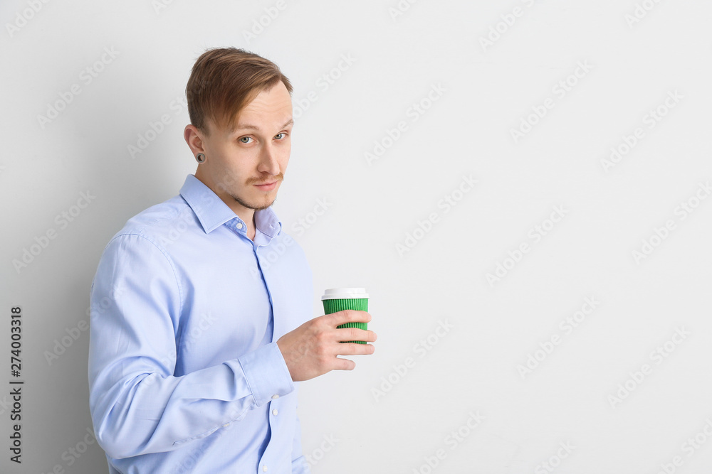 Handsome businessman with cup of coffee on light background Handsome businessman with cup of coffee on light background