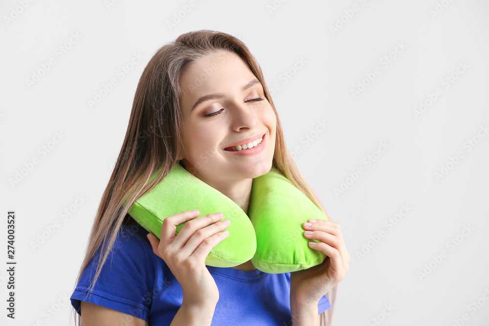 Young woman with travel pillow on light background Young woman with travel pillow on light background