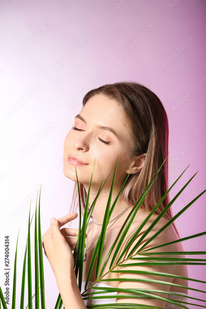 Naklejka premium Young woman with closed eyes and green palm leaf, natural beauty and skincare concept, wellness and relaxation