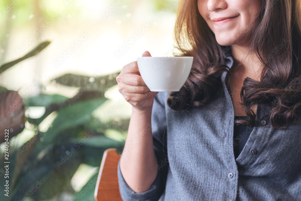 Closeup image of a beautiful woman holding and drinking hot coffee in cafe Closeup image of a beautiful woman holding and drinking hot coffee in cafe