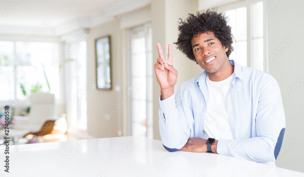 African American man at home smiling with happy face winking at the camera doing victory sign. Number two.