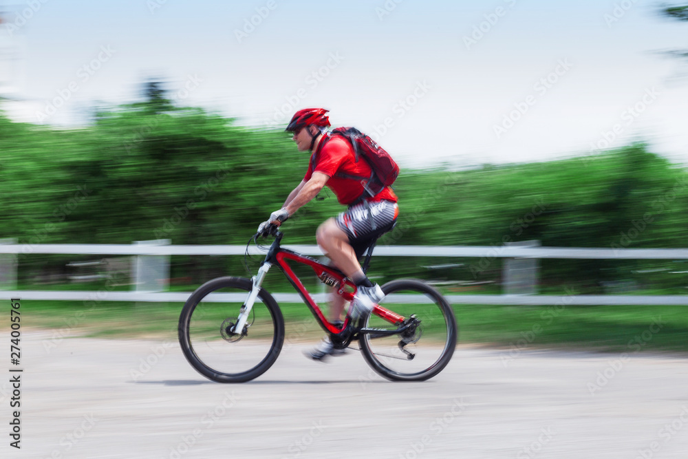 Bicycle rider in the park, it's a sunny summer day. Motion blured image.Blurry Focus. Bicycle rider in the park, it's a sunny summer day. Motion blured image.Blurry Focus.