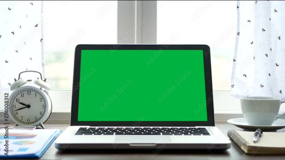 4K. laptop computer with a green screen chroma key set on work office table near the window with white curtain blow 4K. laptop computer with a green screen chroma key set on work office table near the window with white curtain blow