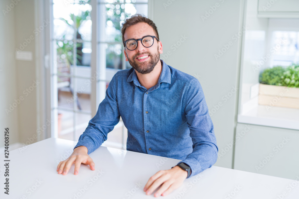 Handsome man wearing glasses and smiling relaxed at camera