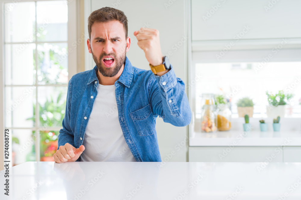 Handsome man at home angry and mad raising fist frustrated and furious while shouting with anger. Rage and aggressive concept. Handsome man at home angry and mad raising fist frustrated and furious while shouting with anger. Rage and aggressive concept.