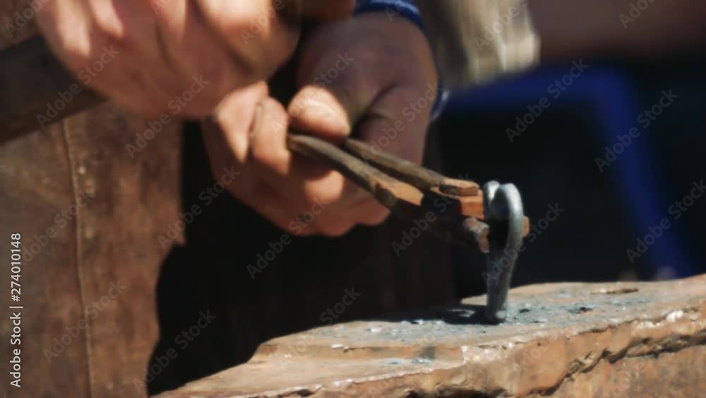 The blacksmith manually forged a heart out of metal. With a hammer and tongs, he corrects the shape of a metal heart. Close up. The blacksmith manually forged a heart out of metal. With a hammer and tongs, he corrects the shape of a metal heart. Close up.