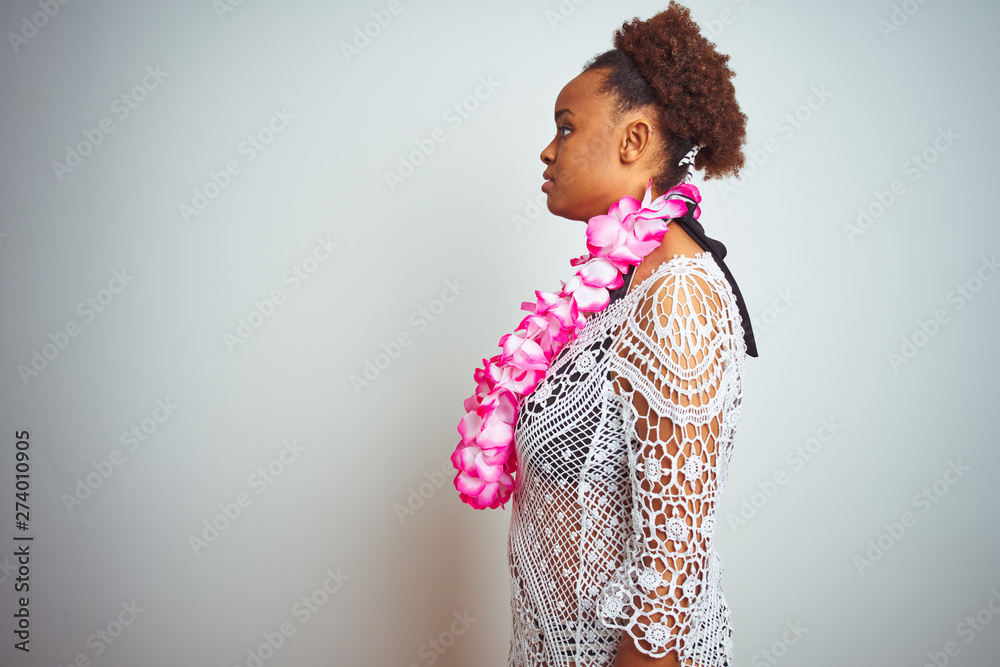 Young african american woman with afro hair wearing flower hawaiian lei over isolated background looking to side, relax profile pose with natural face with confident smile. Young african american woman with afro hair wearing flower hawaiian lei over isolated background looking to side, relax profile pose with natural face with confident smile.