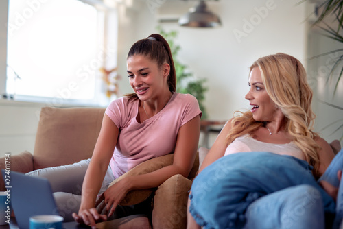 Female friends using laptop at home
