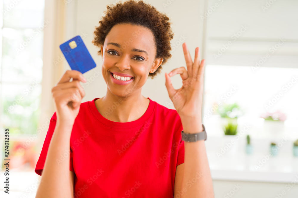 Young african american woman holding credit card doing ok sign with fingers, excellent symbol Young african american woman holding credit card doing ok sign with fingers, excellent symbol