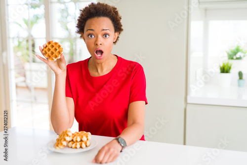 Young african american woman eating sweet waffle scared in shock with a surprise face  afraid and excited with fear expression