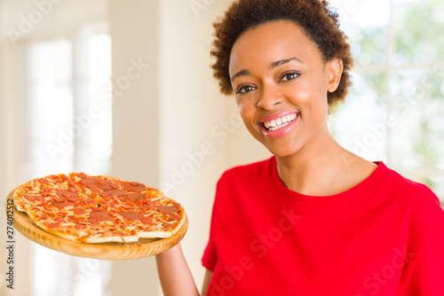 Beautiful young african american woman showing homemade tasty pizza