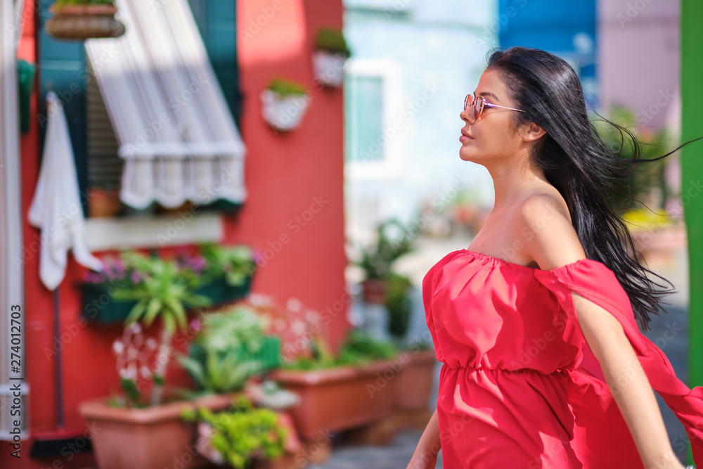 happy tourist woman posing among colorful houses on Burano island, Venice. Tourism in Italy concept