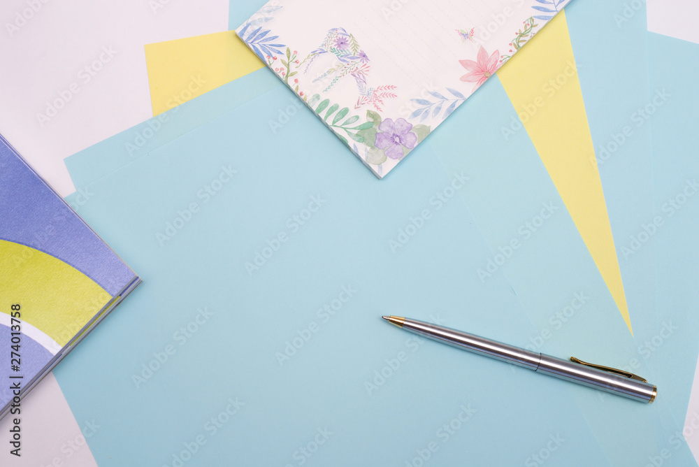 ballpoint pen lies on sheets of blue and yellow paper next to the notebook, white background, layout, Flatley ballpoint pen lies on sheets of blue and yellow paper next to the notebook, white background, layout, Flatley