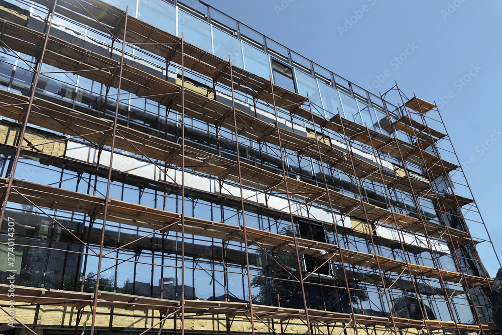 Scaffolding frame on a modern glass building, industrial construction site concept. construction of new stores and supermarkets in the city.