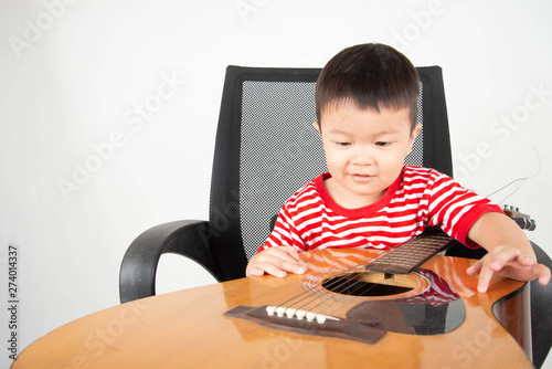 Little todler Asian boy playing guitar