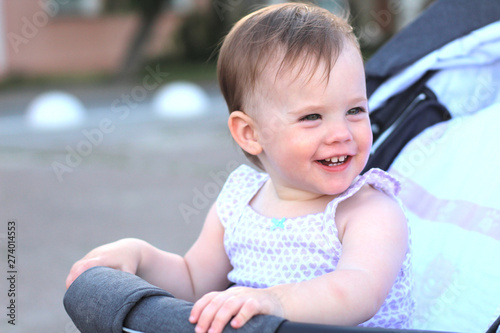 little, beautiful, smiling, cute redhead baby in a pram out-of-doors in a sleeveless shirt © PeterPike