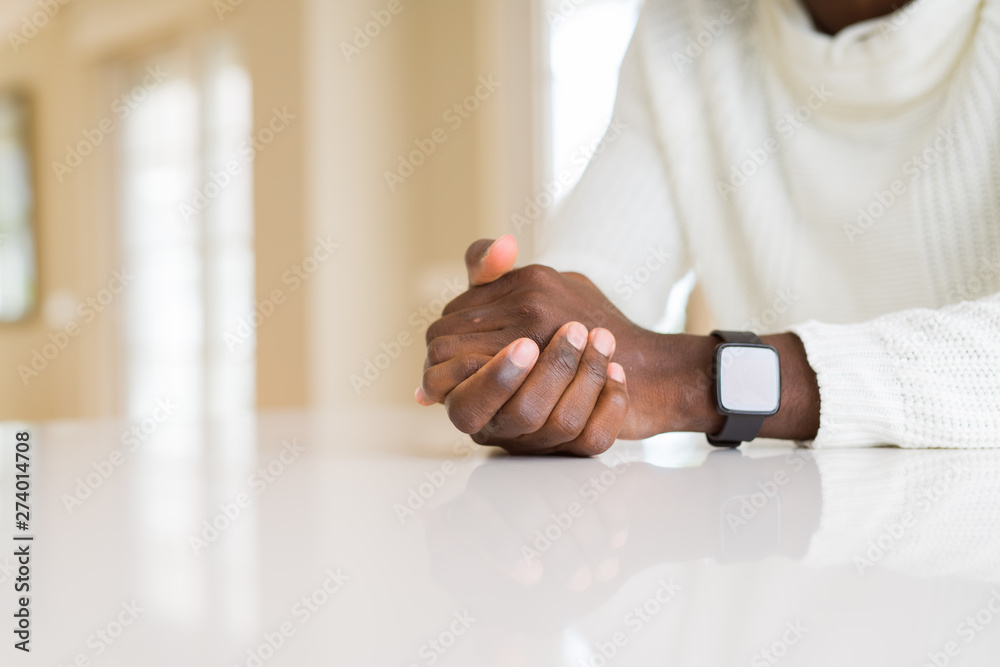 Close up of crossed hands of african man over table