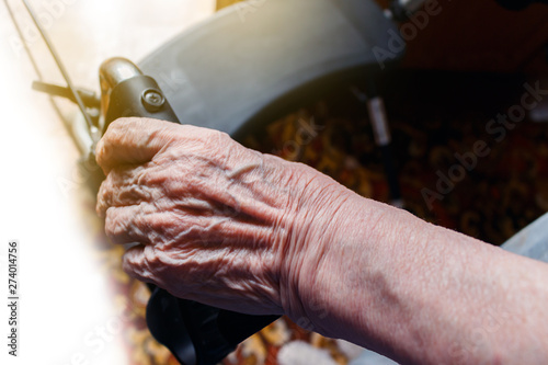 the wrinkled hand of an old caucasian woman holding a walking aid, view from above. care for old people concept.