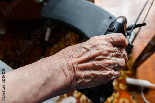 the wrinkled hand of an old caucasian woman holding a walking aid, view from above. old patient woman standing with her hand on a walker stand with wheels. care for old people concept.