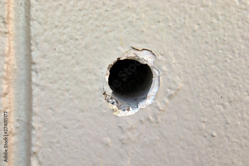 Bullet hole in the white concrete wall, copy space