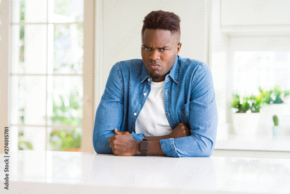 Handsome african american man at home skeptic and nervous, disapproving expression on face with crossed arms. Negative person.