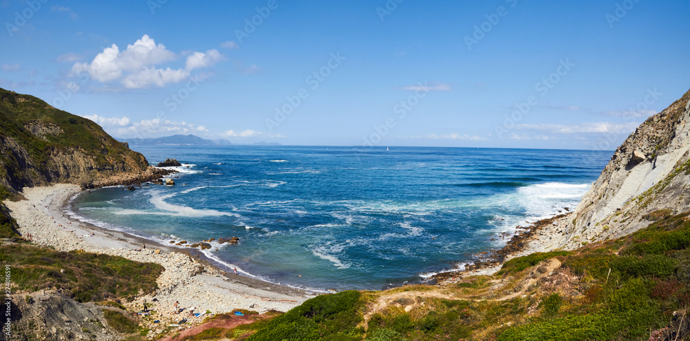 Blue Bizkaia beach in basque country with some surfers