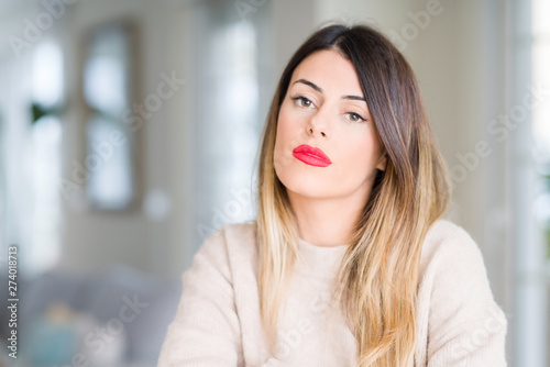 Young beautiful woman wearing winter sweater at home skeptic and nervous  disapproving expression on face with crossed arms. Negative person.
