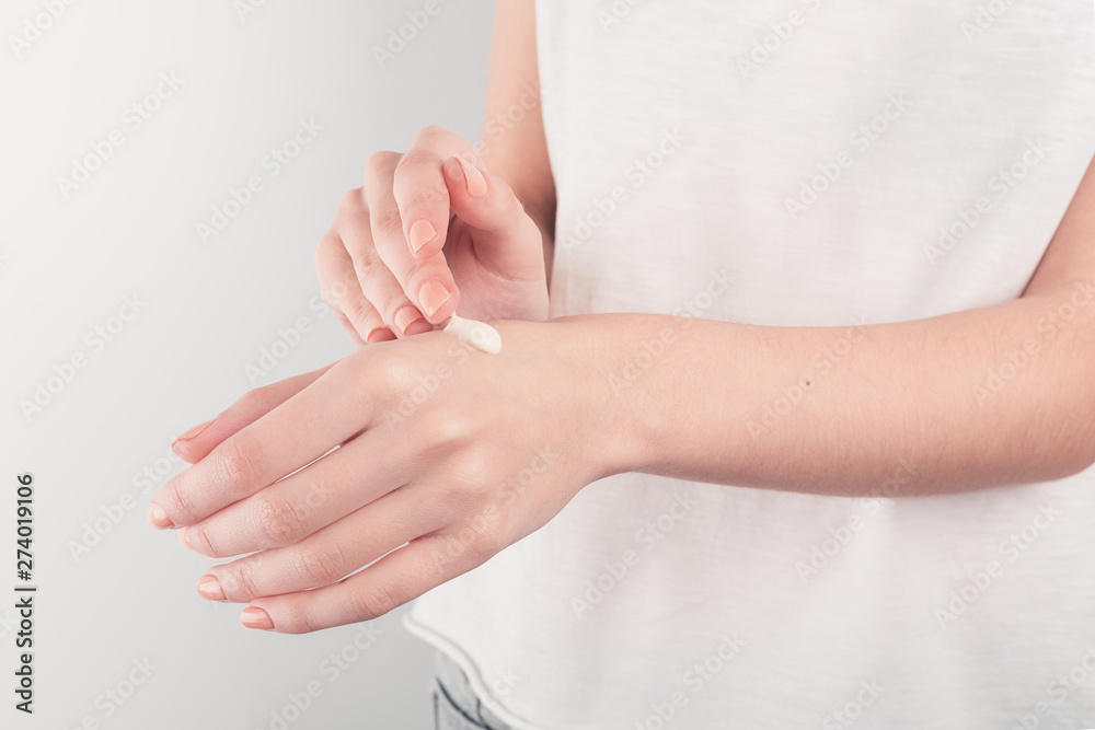 Spa treatment. Close Up of female hands applying hand cream. Woman holding cream tube and applying moisturizer cream on her beautiful hands for clean and soft skin.