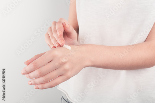 Spa treatment. Close Up of female hands applying hand cream. Woman holding cream tube and applying moisturizer cream on her beautiful hands for clean and soft skin. © stas_malyarevsky