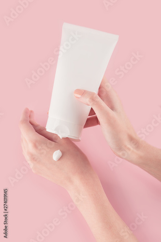 Spa treatment. Close Up of female hands applying hand cream. Woman holding cream tube and applying moisturizer cream on her beautiful hands for clean and soft skin.