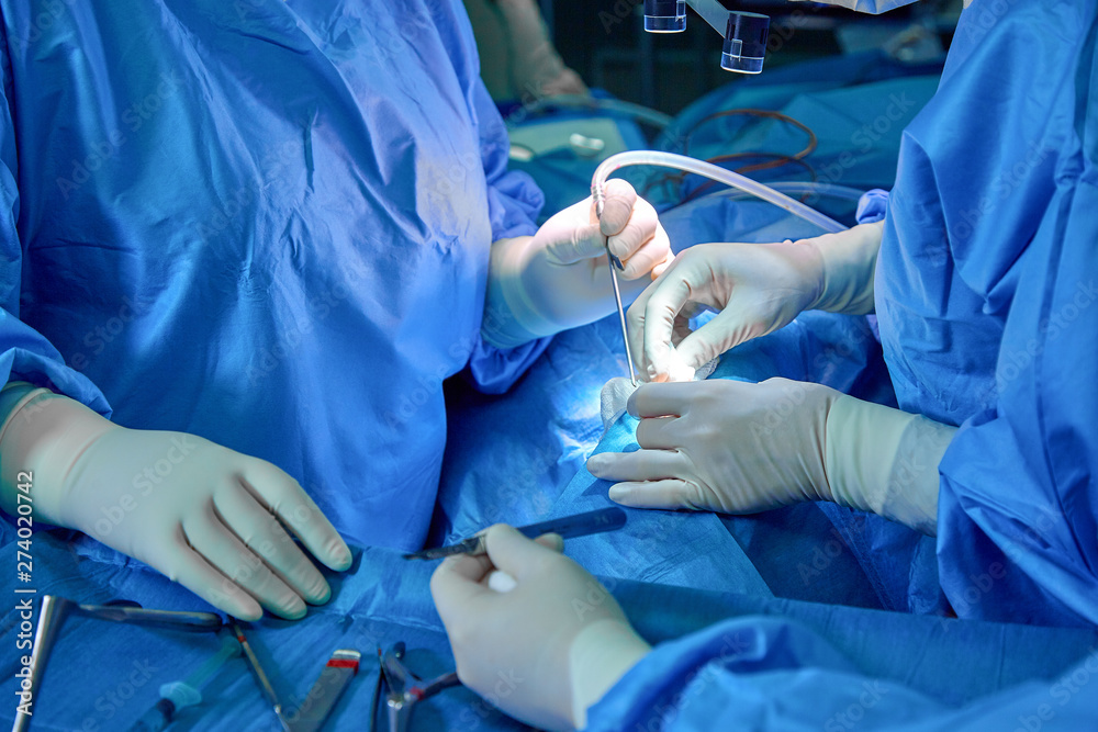 Surgeon and his assistant performing cosmetic surgery on nose in hospital operating room. Nose reshaping, augmentation. Rhinoplasty. Surgeon and his assistant performing cosmetic surgery on nose in hospital operating room. Nose reshaping, augmentation. Rhinoplasty.