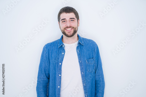 Young handsome hispanic man wearing denim jacket over white isolated background with a happy and cool smile on face. Lucky person.
