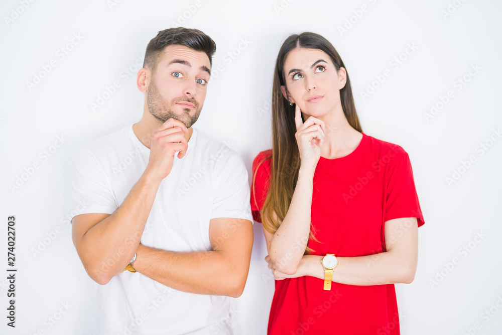 Young beautiful couple together over white isolated background with hand on chin thinking about question, pensive expression. Smiling with thoughtful face. Doubt concept. Young beautiful couple together over white isolated background with hand on chin thinking about question, pensive expression. Smiling with thoughtful face. Doubt concept.