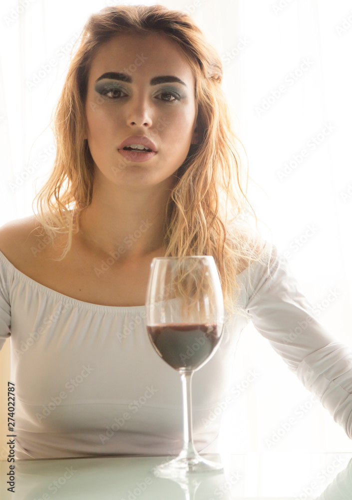 Young beautiful woman with glass of red wine on light background Young beautiful woman with glass of red wine on light background