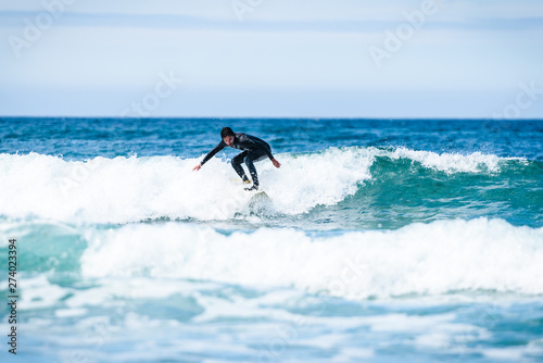 Surfer guy surfing with surfboard on waves in Atlantic ocean.