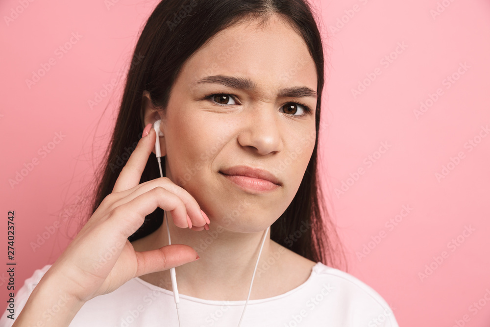 Portrait closeup of disappointed young girl frowning while wearing earphones Portrait closeup of disappointed young girl frowning while wearing earphones
