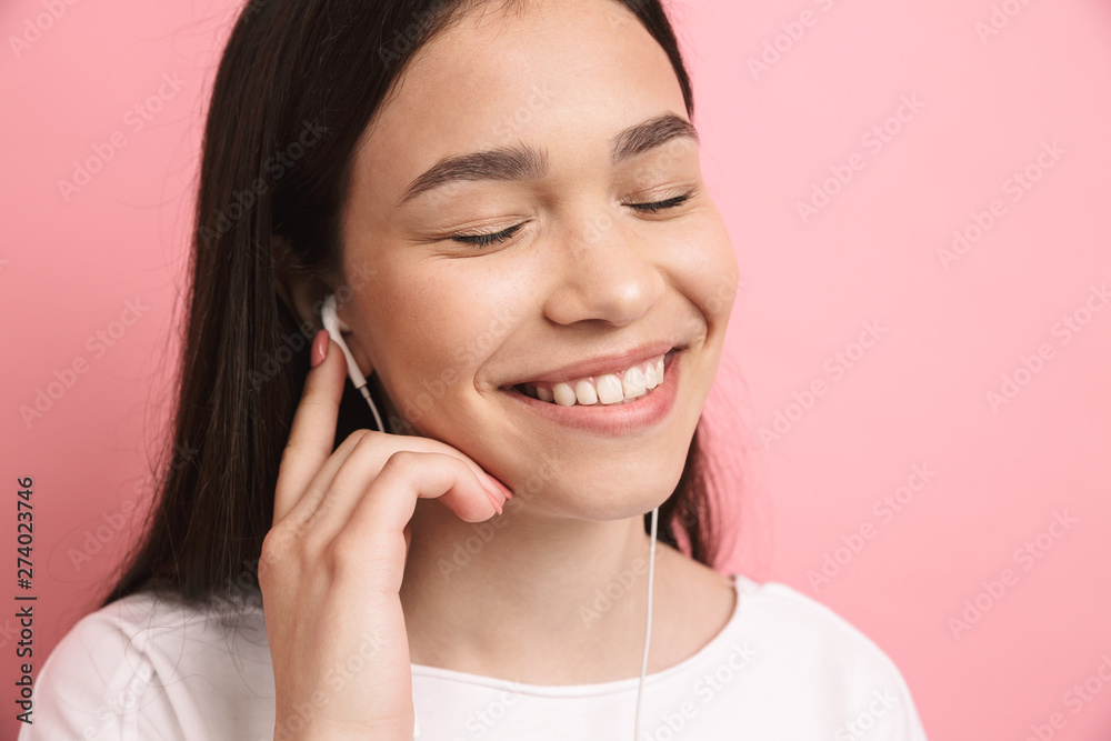 Portrait closeup of optimistic caucasian girl wearing earphones smiling while listening to music