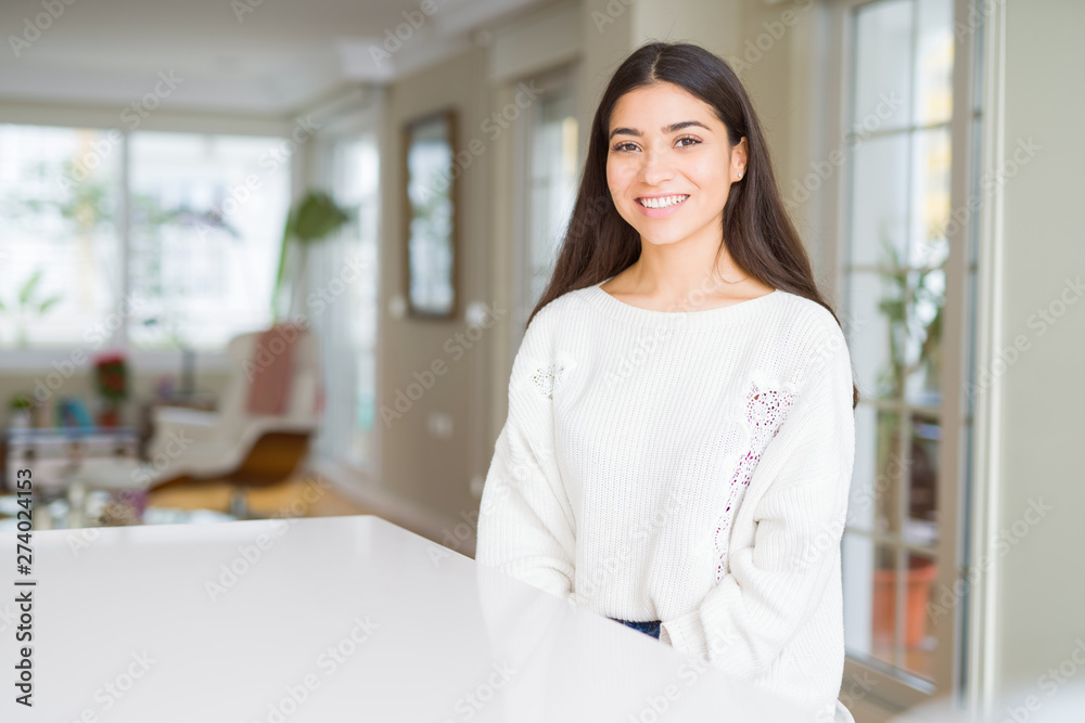Young beautiful woman at home on white table with a happy and cool smile on face. Lucky person. Young beautiful woman at home on white table with a happy and cool smile on face. Lucky person.