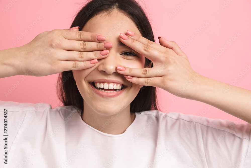 Portrait closeup of charming optimistic girl with long dark hair covering her eyes and peeking though hands Portrait closeup of charming optimistic girl with long dark hair covering her eyes and peeking though hands