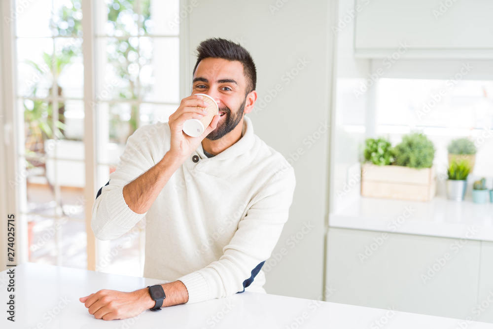 Handsome man smiling while enjoying drinking a take away coffee in the morning Handsome man smiling while enjoying drinking a take away coffee in the morning
