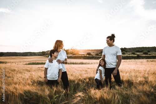 Funny happy family smiling in the field sunset