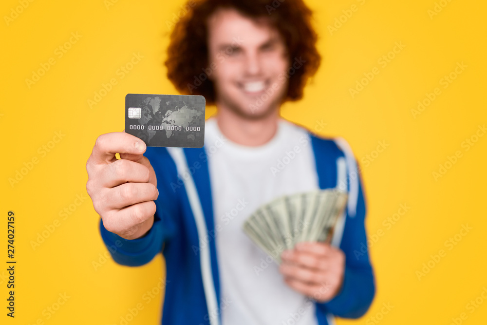 Blurred guy with money demonstrating credit card Blurred guy with money demonstrating credit card