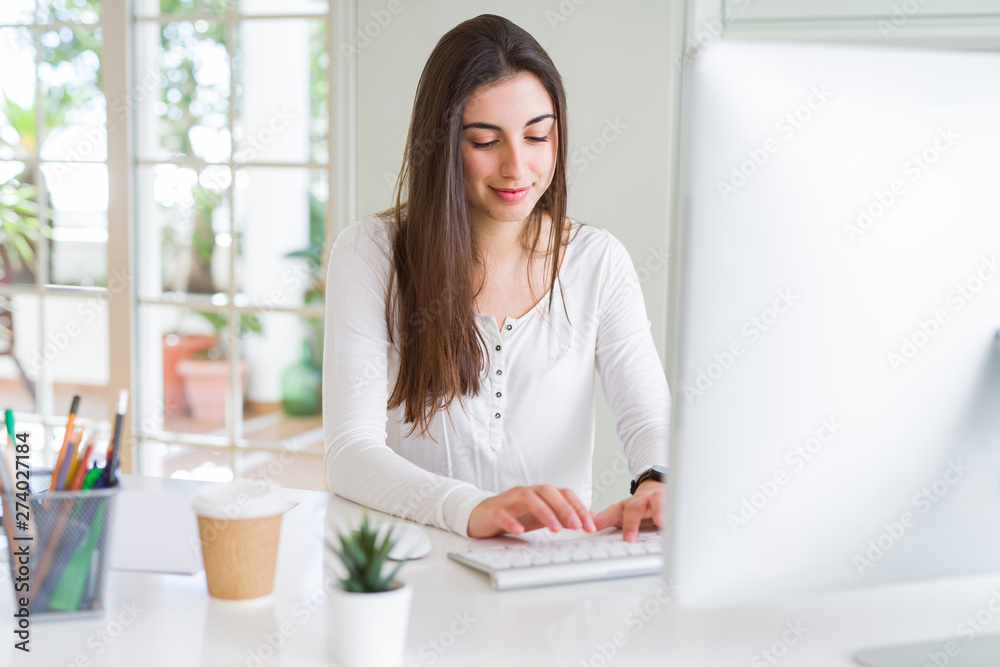 Beautiful young business woman working using computer, smiling and concentrated on online work Beautiful young business woman working using computer, smiling and concentrated on online work
