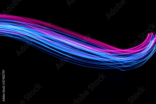 Long exposure, light painting photography.  Vibrant electric blue and neon pink streaks of colour against a black background photo