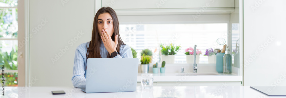 Wide angle picture of beautiful young woman working or studying using laptop cover mouth with hand shocked with shame for mistake, expression of fear, scared in silence, secret concept