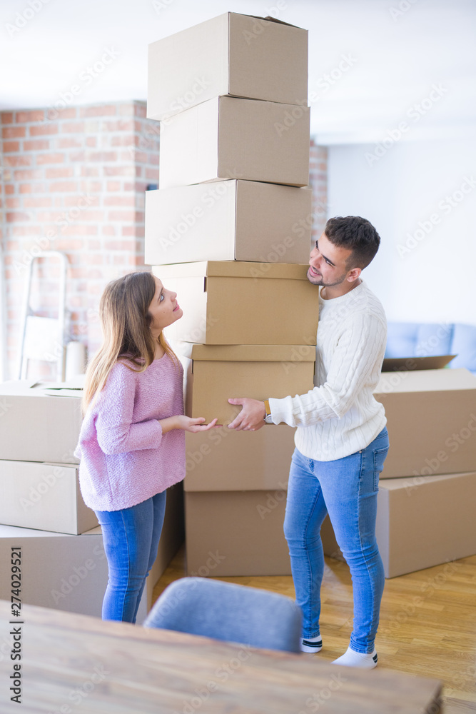 Young beautiful couple in love moving to new home, holding cardboard boxes very happy and cheerful for new apartment Young beautiful couple in love moving to new home, holding cardboard boxes very happy and cheerful for new apartment