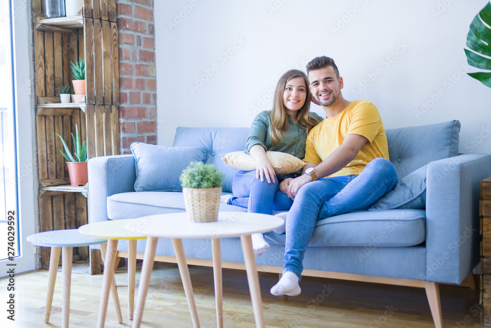 Young beautiful couple sitting hugging in love on the sofa at home Young beautiful couple sitting hugging in love on the sofa at home