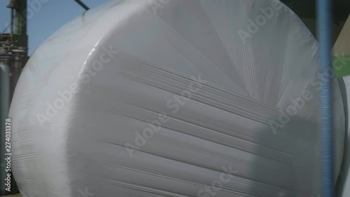 Machine is wrapping hay bales on the field