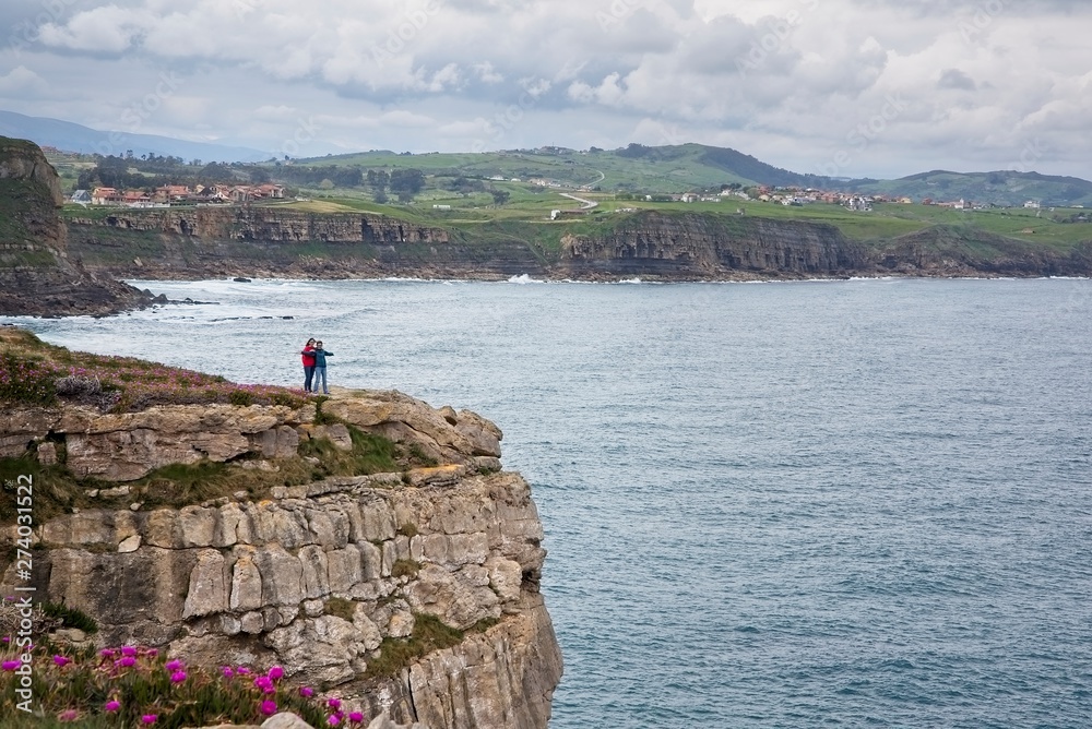 Two people enjoy the scenery at the edge of the cliff Two people enjoy the scenery at the edge of the cliff